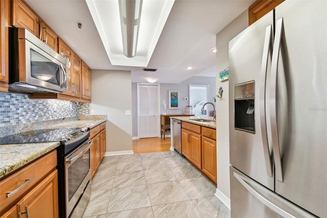 kitchen featuring decorative backsplash, appliances with stainless steel finishes, sink, and light stone counters