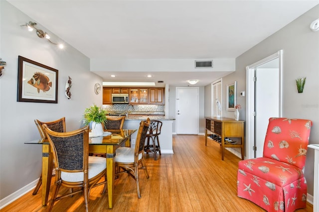 dining space with light wood-type flooring and sink