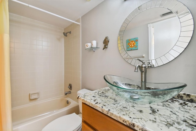 full bathroom with tiled shower / bath, vanity, and toilet