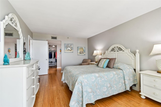 bedroom with light wood-type flooring, a spacious closet, and a closet