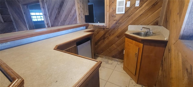 bar with sink, light tile patterned flooring, and wood walls