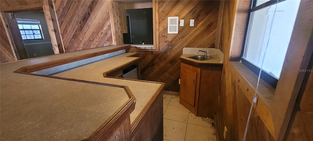 bar featuring sink, wooden walls, and light tile patterned flooring