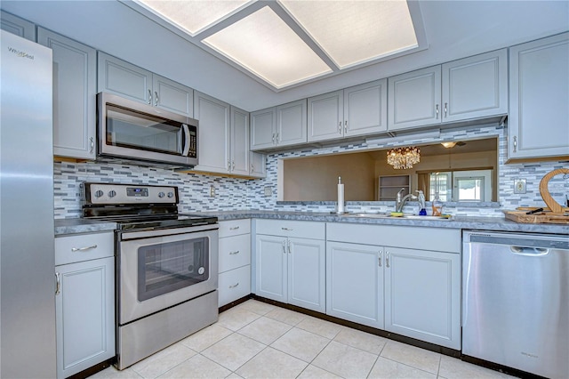 kitchen with sink, light tile patterned flooring, decorative backsplash, and stainless steel appliances