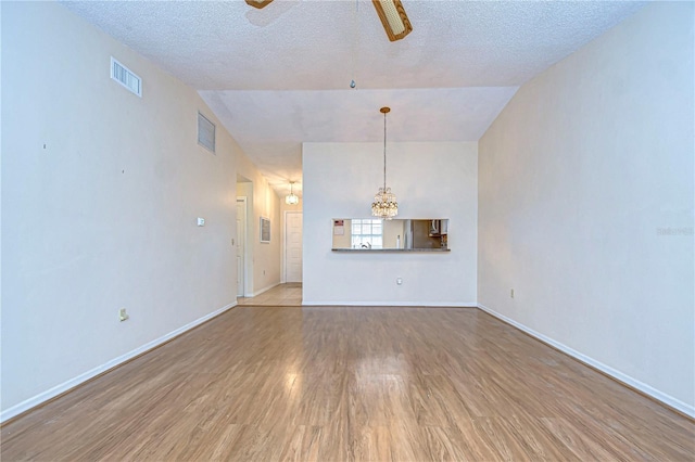 unfurnished living room with lofted ceiling, a textured ceiling, wood-type flooring, and ceiling fan