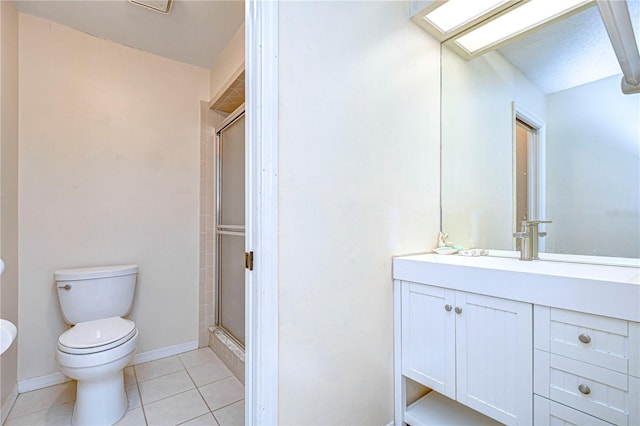 bathroom with toilet, a shower with shower door, a skylight, vanity, and tile patterned flooring