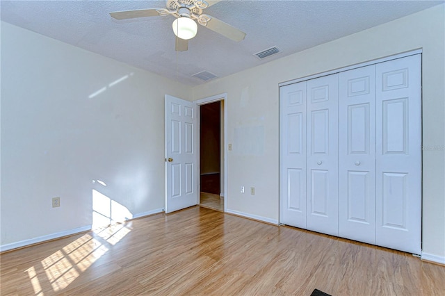 unfurnished bedroom featuring light hardwood / wood-style flooring, a textured ceiling, a closet, and ceiling fan