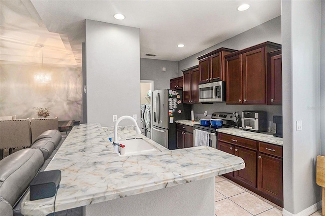 kitchen featuring sink, light tile patterned floors, a breakfast bar, appliances with stainless steel finishes, and light stone counters