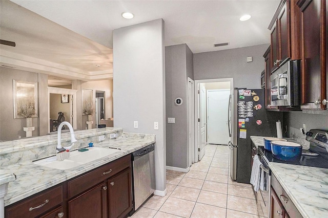 kitchen featuring light stone counters, sink, light tile patterned floors, and appliances with stainless steel finishes