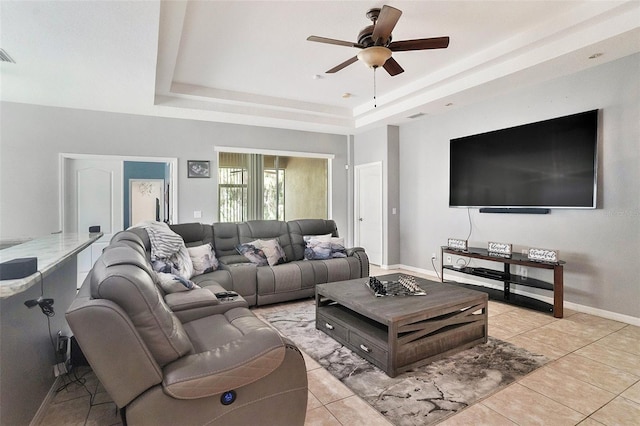 tiled living room featuring ceiling fan and a tray ceiling