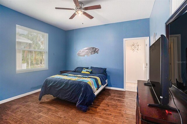 bedroom with dark hardwood / wood-style flooring and ceiling fan