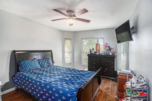 bedroom featuring dark hardwood / wood-style flooring, ceiling fan, and a textured ceiling