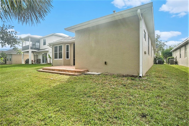 rear view of house featuring a yard, a balcony, and central air condition unit