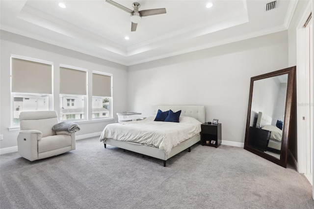 carpeted bedroom with ornamental molding, ceiling fan, and a raised ceiling