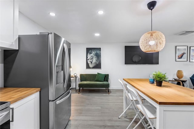 kitchen with white cabinetry, light hardwood / wood-style floors, hanging light fixtures, and wood counters