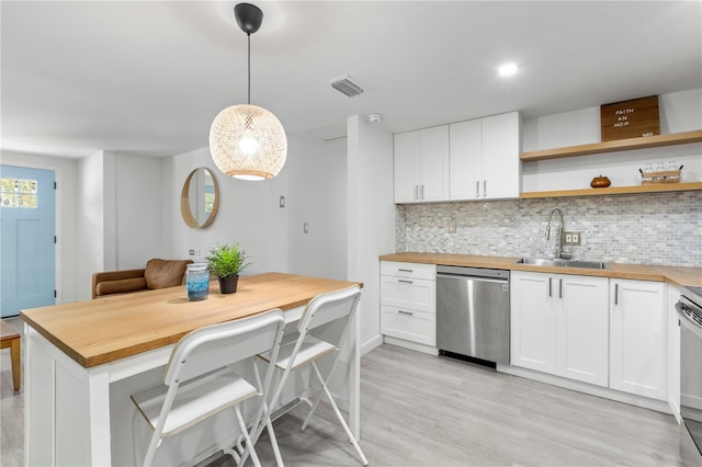 kitchen with stainless steel appliances, butcher block counters, and white cabinetry