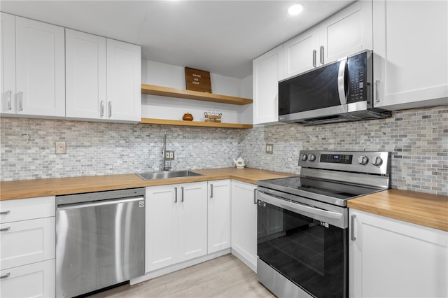 kitchen featuring butcher block countertops, tasteful backsplash, appliances with stainless steel finishes, sink, and white cabinets