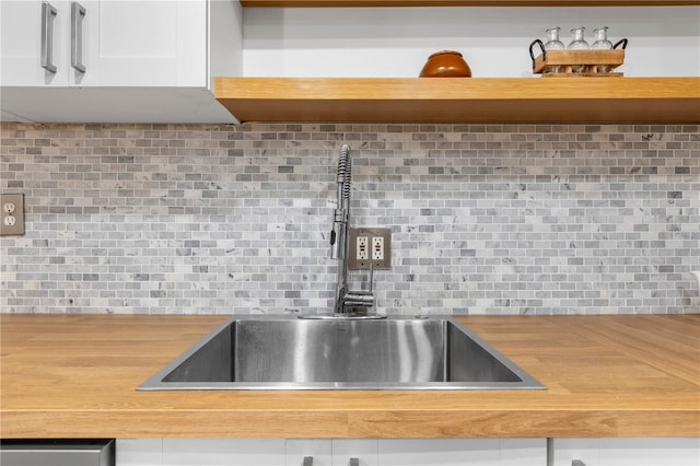 room details featuring sink, white cabinetry, and decorative backsplash