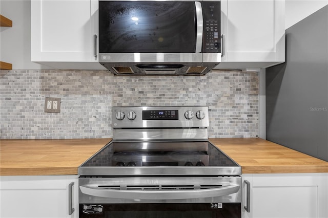 kitchen with white cabinets, butcher block countertops, backsplash, and appliances with stainless steel finishes