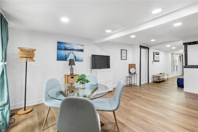 dining room featuring a wall mounted AC and light hardwood / wood-style floors