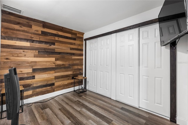 unfurnished bedroom featuring wooden walls, a closet, and dark hardwood / wood-style flooring