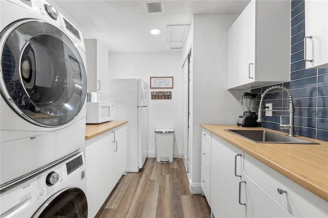 laundry room with stacked washer and dryer, sink, and light wood-type flooring