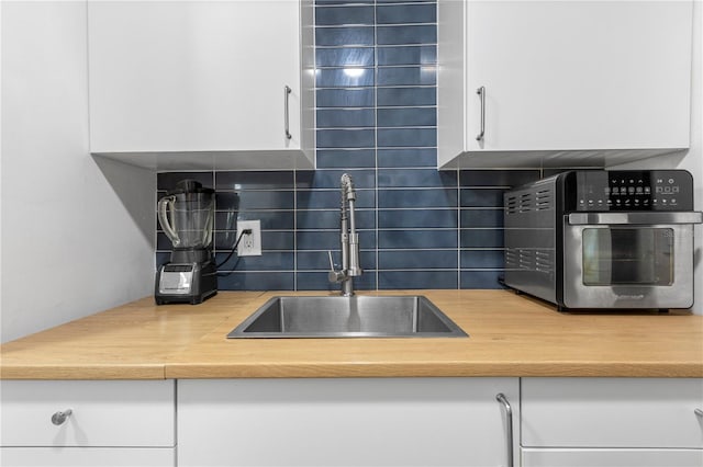 kitchen with white cabinets, decorative backsplash, and sink