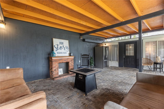 living room featuring a brick fireplace and beam ceiling