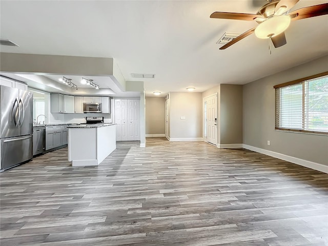 kitchen with appliances with stainless steel finishes, light hardwood / wood-style flooring, a kitchen island, and gray cabinets