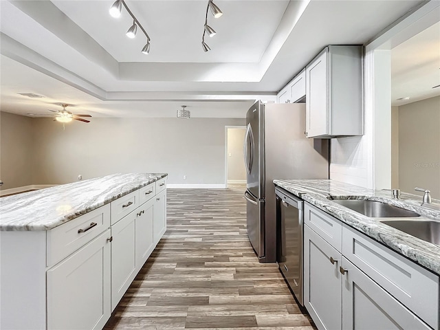 kitchen featuring light wood-type flooring, stainless steel dishwasher, white cabinetry, light stone counters, and ceiling fan