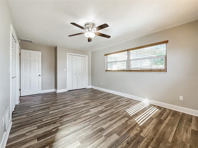 unfurnished bedroom with dark hardwood / wood-style flooring, a closet, and ceiling fan