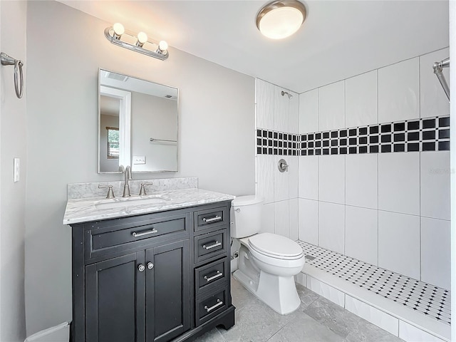 bathroom with toilet, vanity, and a tile shower