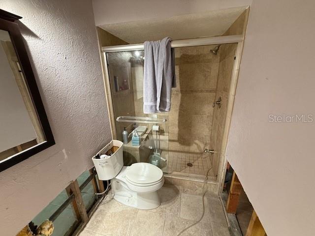 bathroom with toilet and an enclosed shower