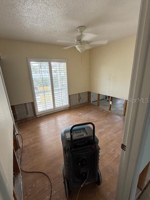 spare room featuring a textured ceiling, wood-type flooring, and ceiling fan