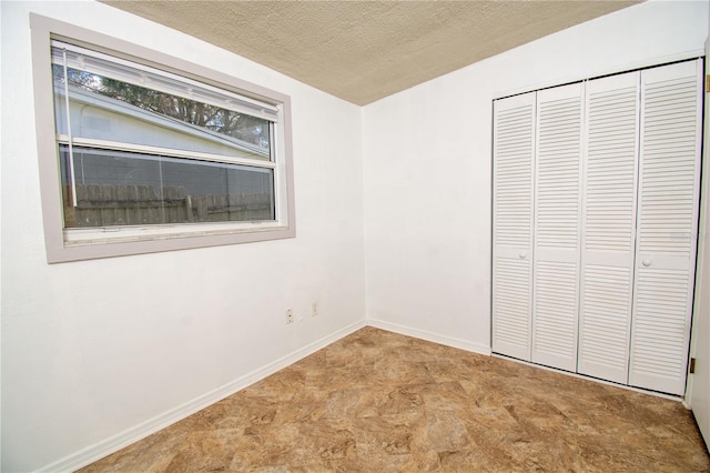 unfurnished bedroom featuring a textured ceiling and a closet