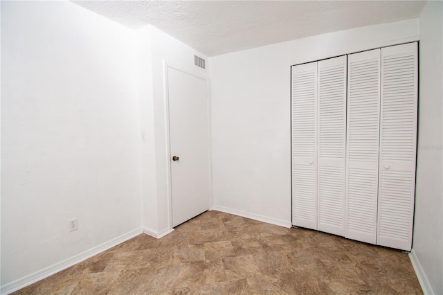 unfurnished bedroom with a textured ceiling and a closet