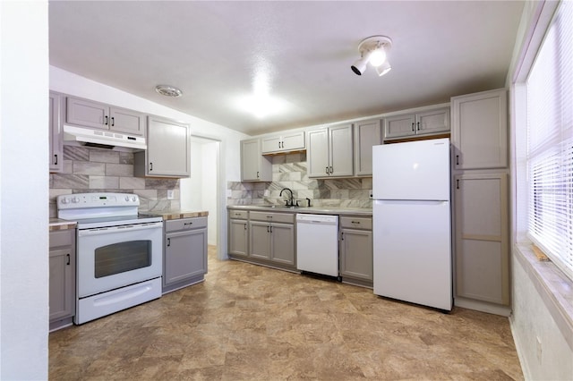 kitchen with tasteful backsplash, sink, gray cabinetry, and white appliances