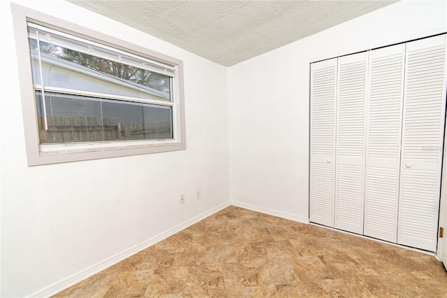 unfurnished bedroom featuring a textured ceiling and a closet