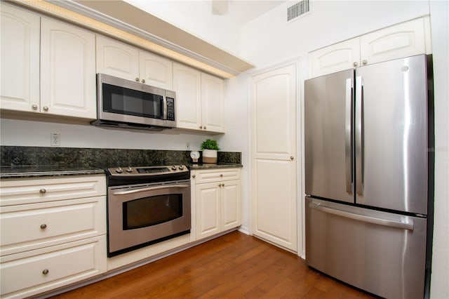 kitchen with dark stone countertops, dark hardwood / wood-style flooring, white cabinetry, and stainless steel appliances