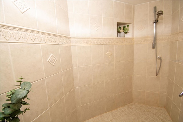 bathroom with tiled shower and tile walls