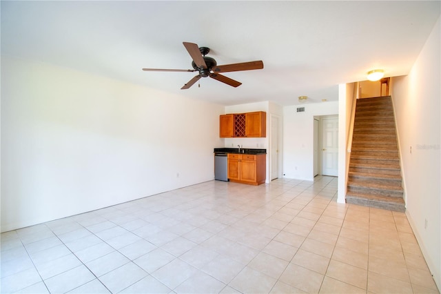 unfurnished living room with ceiling fan, light tile patterned floors, and bar area