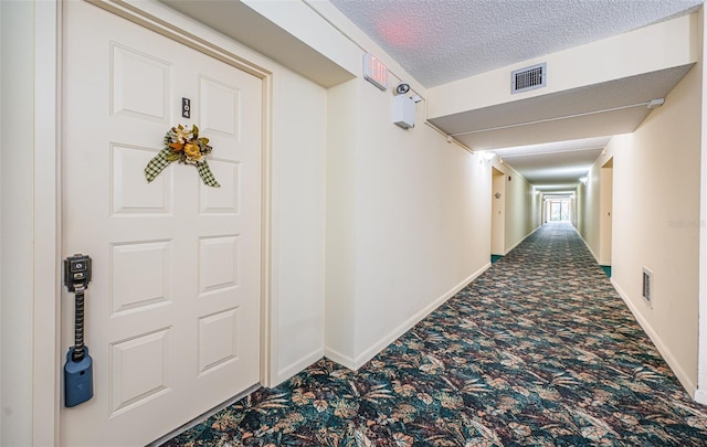 hall with carpet floors and a textured ceiling