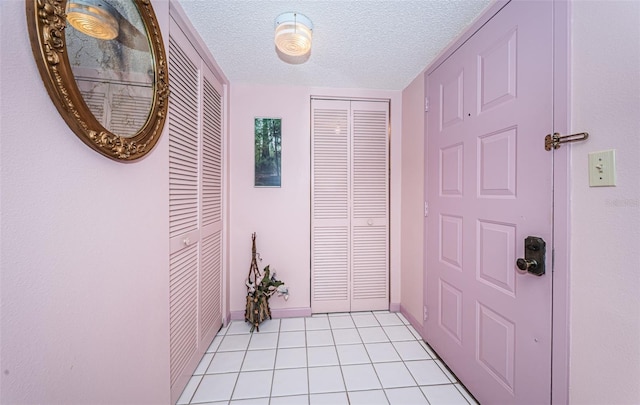 hall with light tile patterned floors and a textured ceiling