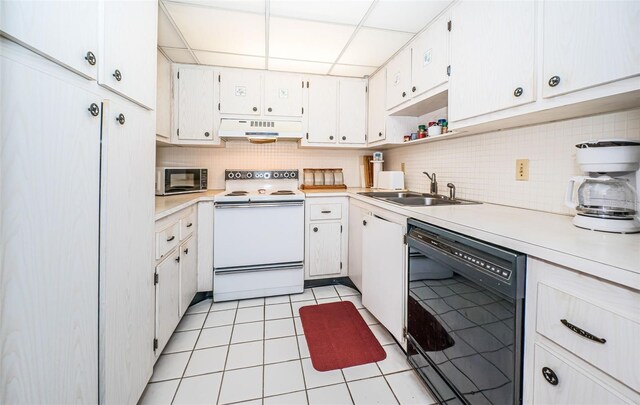 kitchen with a paneled ceiling, sink, black appliances, light tile patterned floors, and white cabinetry