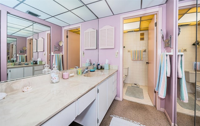 bathroom with toilet, a tile shower, vanity, and tile patterned floors