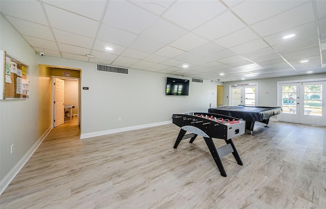 recreation room with a paneled ceiling, french doors, and light wood-type flooring