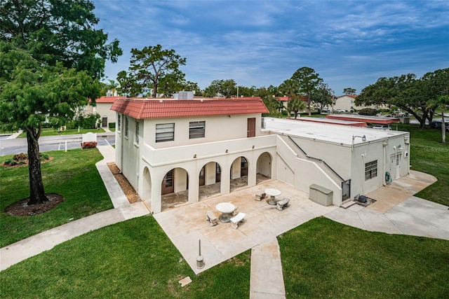 back of property featuring a patio, a balcony, and a lawn