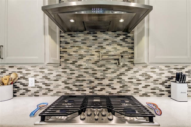 kitchen featuring tasteful backsplash, white cabinetry, stainless steel gas cooktop, and range hood