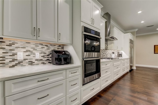 kitchen with white cabinetry, wall chimney exhaust hood, stainless steel appliances, tasteful backsplash, and dark hardwood / wood-style floors