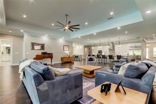 living room featuring a tray ceiling, ceiling fan, and wood-type flooring