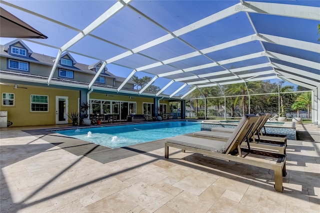 view of swimming pool featuring glass enclosure, pool water feature, ceiling fan, an in ground hot tub, and a patio